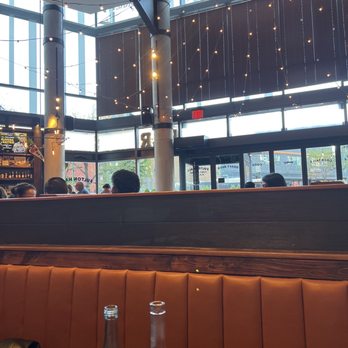 Fulton Hall - A sports bar interior featuring large windows, string lights hanging from the ceiling, and patrons seated at tables. The space has a modern design with high ceilings and visible outdoor views. - Pubs Near Me - Brooklyn, New York