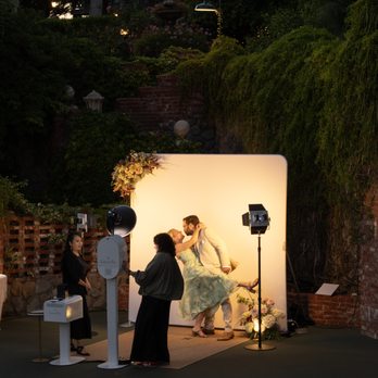 Luxelle Photo Booth - Couple taking a romantic picture in front of the Luxelle DSLR Photobooth with "The Pearly White" backdrop with floral addition - Photo Booth Rentals Near Me - Ontario, California Luxelle Photo Booth - Couple taking a romantic picture in front of the Luxelle DSLR Photobooth with "The Pearly White" backdrop with floral addition - Photo Booth Rentals Near Me - Ontario, California