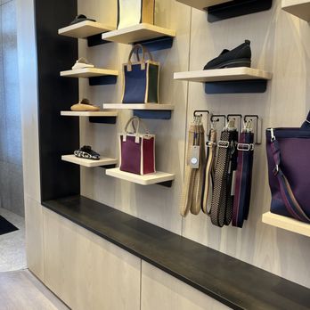 Rothy's - The image features a retail display with multiple wall-mounted shelves and hooks. Handbags in various colors and styles are placed on the shelves, while shoes are displayed on the upper shelves. Accessories such as belts are hanging on hooks. The display is organized against a light-colored wall with a black and wood-tone base, creating a clean and modern presentation. - Shoe Stores Near Me - Washington, DC, District of Columbia
