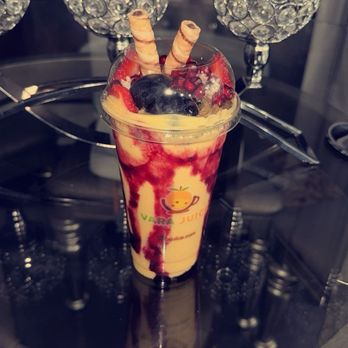 Vara juice - Arisi smoothie blend - A fruit smoothie topped with berries and wafer sticks, served in a clear cup with the Vara Juice logo, on a reflective black surface. - Juice Bars & Smoothies Near Me - Bridgeview, Illinois