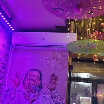 Fitoor Cafe & Grill - a mural of a man holding an umbrella - Hookah Bars Near Me - Fresh Meadows, New York