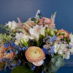 Mona Floral Design - Soft pastel floral arrangement featuring ranunculus and delicate blue accents, perfect for an elegant, whimsical touch.