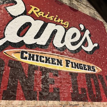 Raising Cane's Chicken Fingers - a sign on the side of a building - Fast Food Near Me - Hurst, Texas Raising Cane's Chicken Fingers - a sign on the side of a building - Fast Food Near Me - Hurst, Texas