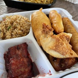 Crab Rangoon - A plastic takeout container holds fried rice, an egg roll, spring roll, and ribs, with another dish visible in the background.