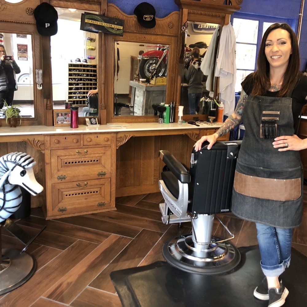 Brooke's Two Bit Barbershop - Brooke in front of a Victorian era custom breakfront fitted to accommodate the barbering equipment - Barbers Near Me - Fort Collins, Colorado Brooke's Two Bit Barbershop - Brooke in front of a Victorian era custom breakfront fitted to accommodate the barbering equipment - Barbers Near Me - Fort Collins, Colorado