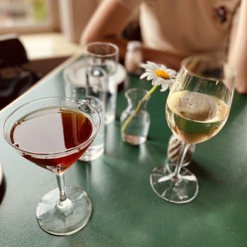 Place Pigalle - a woman sitting at a table with a glass of wine - French Near Me - Seattle, Washington