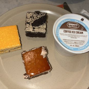Hong Kong Buffet - A beige plate holds three small dessert pieces: a yellow cake, a chocolate cake, and a caramel-topped dessert, with a cup of Hershey's coffee ice cream. - Chinese Near Me - Cranston, Rhode Island