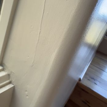 JPM Services - High gloss over flat unapproved paint - Close-up of a painted wall showing uneven texture and a corner near a wooden floor, with some imperfections in the paint. - Painters Near Me
