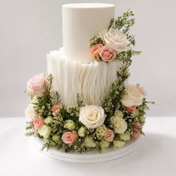La Bouchée - White ruffle wedding cake with blush and ivory roses and fresh greenery around the base