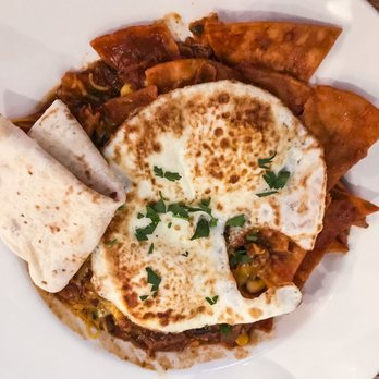 Flo - Red Chilaquiles, $10, feature homemade corn chips, your choice of egg, black beans, corn and pico de gallo, all topped in a flavorful sauce - Breakfast & Brunch Near Me - Chicago, Illinois