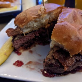 Jackson's Pit - Just look at the jelly! - A burger with a toasted bun, beef patty, and toppings is served on a white plate alongside a lemon wedge. - Burgers Near Me - Negaunee, Michigan