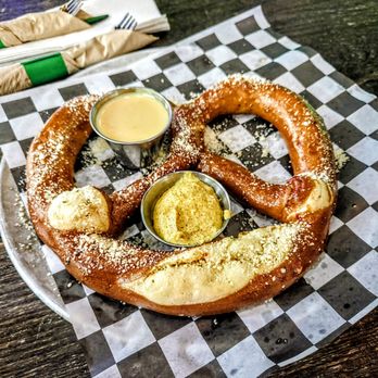 Solace Outpost - Jumbo Pretzel: Served warm, brushed with garlic butter and dusted with parmesan. Served with Solace beer cheese and mustard. - Bars Near Me - Falls Church, Virginia Solace Outpost - Jumbo Pretzel: Served warm, brushed with garlic butter and dusted with parmesan. Served with Solace beer cheese and mustard. - Bars Near Me - Falls Church, Virginia