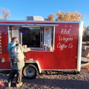 Red Wagon Coffee - Red Wagon Coffee - A red coffee food truck named Red Wagon Coffee Co is parked outdoors, with an open window and a neon 'OPEN' sign. Customers are ordering, and vehicles are parked nearby. - Food Trucks Near Me