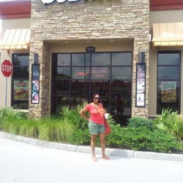 a woman standing in front of a subway restaurant