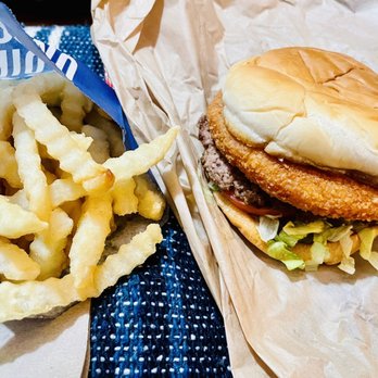 Culver's - Large Fry & The CURDERBURGER - The image shows a fast food meal consisting of a portion of crinkle-cut fries in a blue paper bag and a fried chicken sandwich with lettuce, tomato, and a soft bun. The fries are golden and crispy, while the sandwich includes a breaded fried chicken fillet, fresh lettuce, and a slice of tomato, all assembled in a paper wrapper or tray. - Fast Food Near Me - Beloit, Wisconsin