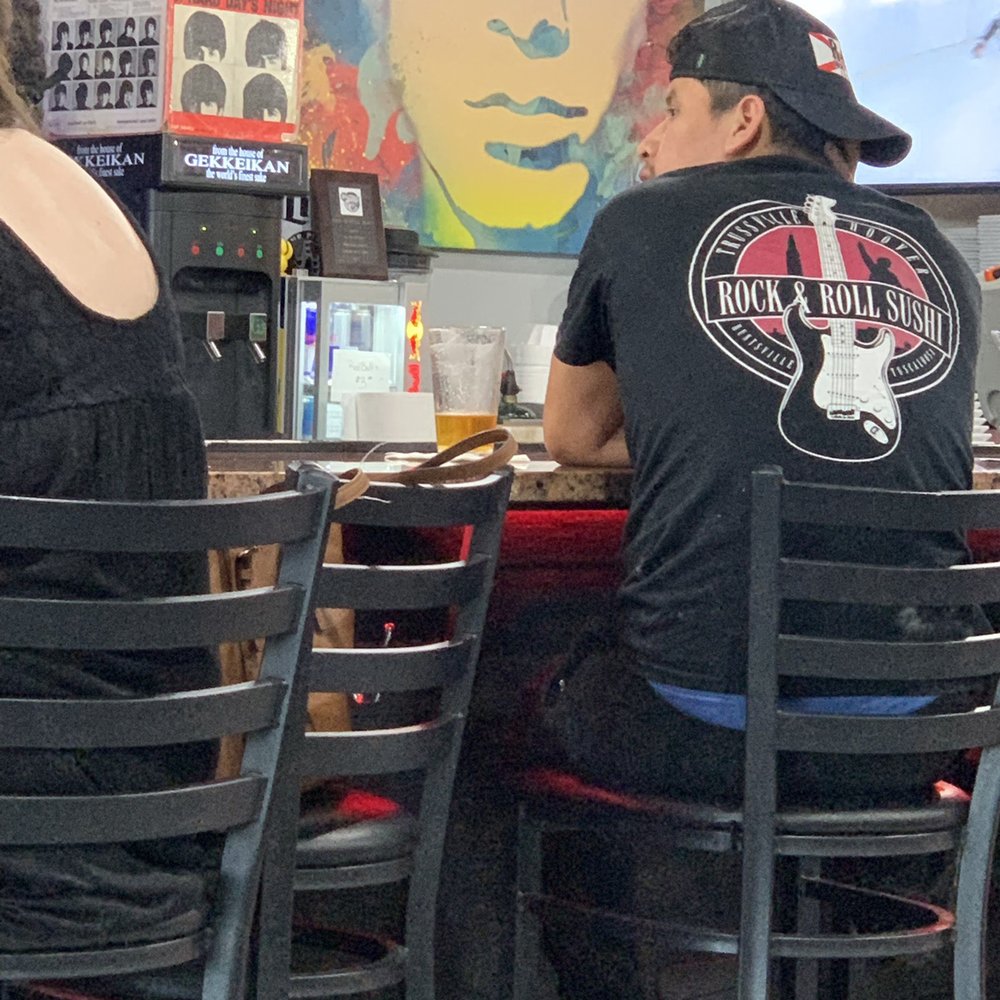 Rock N Roll Sushi - This guy is wearing his employee uniform and having a drink at the restaurant he works. Definitely not acceptable. - Sushi Bars Near Me - Memphis, Tennessee
