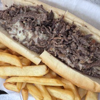 Philly Steaks - A Philly cheesesteak with sliced beef, melted cheese, onions, and peppers in a hoagie roll, served with French fries. - Cheesesteaks Near Me - Stroudsburg, Pennsylvania