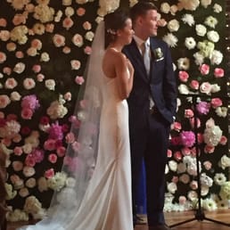 The florist made a beautiful flower wall to serve as the backdrop for this happy couple. The florist made a beautiful flower wall to serve as the backdrop for this happy couple.