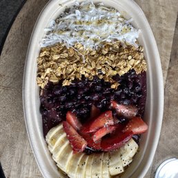 Acai bowl with coconut, granola, blueberries, strawberries, bananas, chia seeds, and honey.