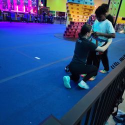 Urban Air Trampoline and Adventure Park - Some of the climbing walls plus a worker helping a student with the harness.