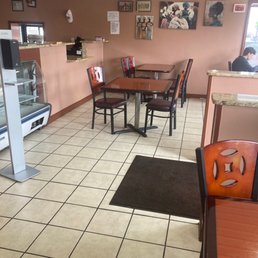 Interior - A dining area with several tables and chairs, wall art, and a small counter, in a casual restaurant setting.