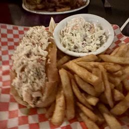 Lobster Roll - A lobster roll served with a side of French fries and coleslaw on a checkered paper-lined tray, likely at a restaurant.