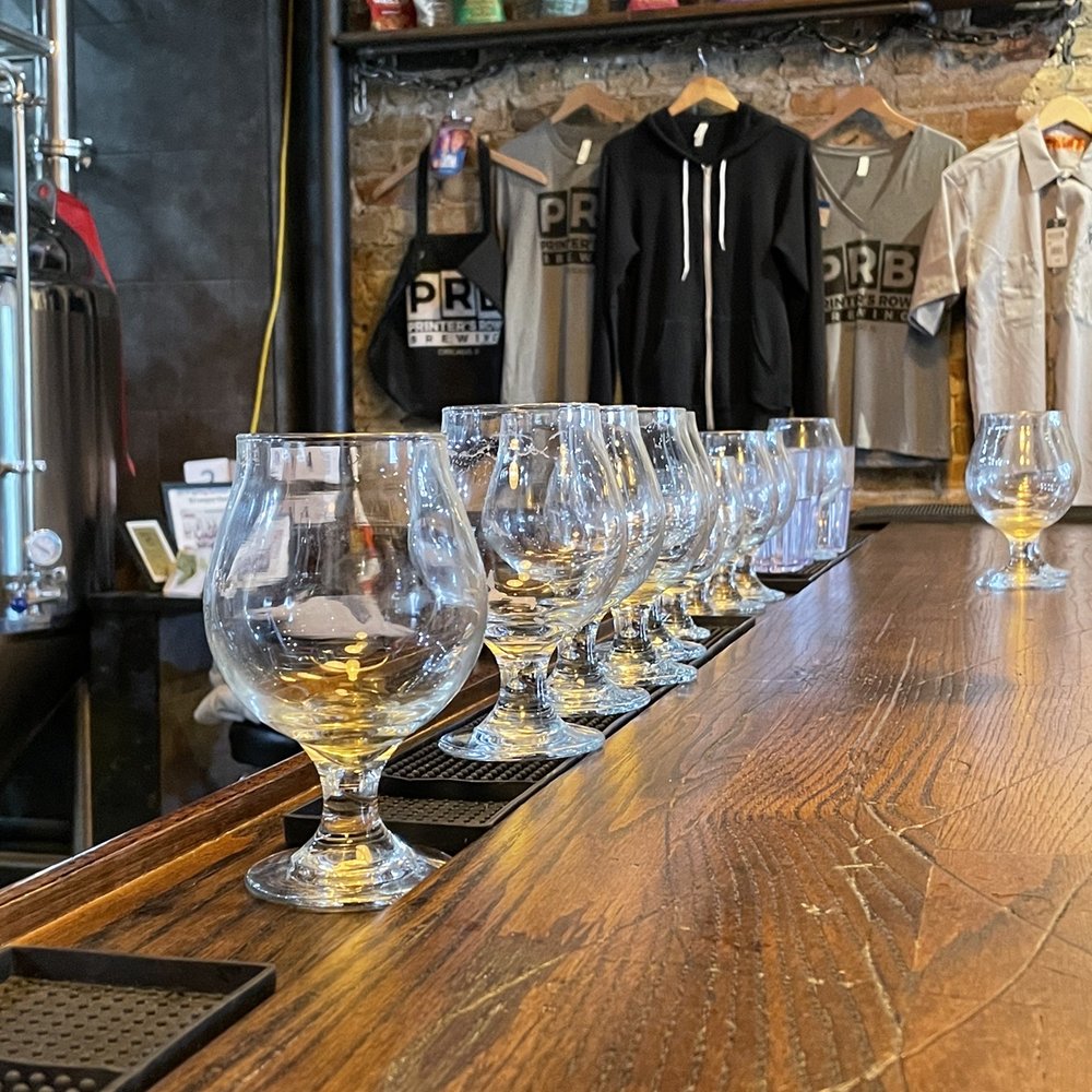 Printer’s Row Brewing - a row of wine glasses on a bar - Breweries Near Me - Chicago, Illinois Printer’s Row Brewing - a row of wine glasses on a bar - Breweries Near Me - Chicago, Illinois