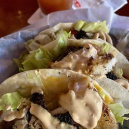 Fish tacos. The grouper sandwich comes with French fries and coleslaw.  You shouldn't have to ask, it says it comes on the menu.