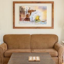 Enchanted Cottages By The Sea - Hollyhock living room with a queen sleeper sofa couch. Photograph of Cape Disappointment Lighthouse
