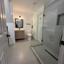 Space 360 - Bathroom built from scratch in former laundry area, now featuring glass door, vanity, toilet, and full walk-in shower.