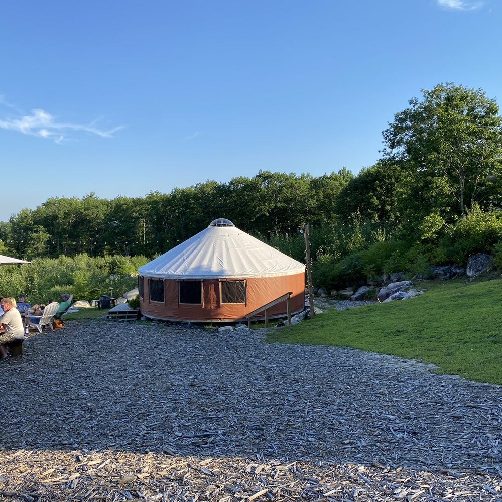 a group of people sitting at picnic tables outside a yurt a group of people sitting at picnic tables outside a yurt