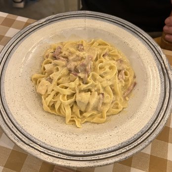 Pastamarket - A dish of fettuccine pasta with a creamy sauce and chunks of ham or bacon, served on a decorative plate at a restaurant. - Italian Near Me - Miami, Florida