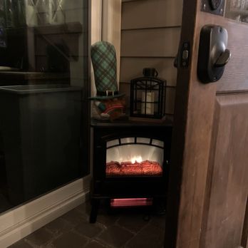Ruby’s Winehouse - Space heater turned on by the owner just for us - A small electric heater with a decorative cover is positioned near a door and window, with a lantern and a plaid hat on top. - Wine Bars Near Me - Coraopolis, Pennsylvania