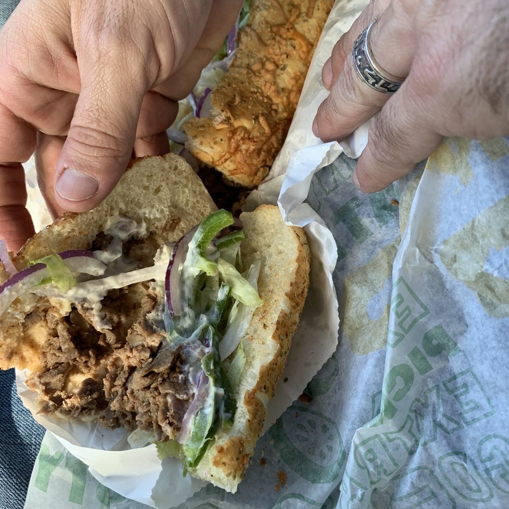 Subway - a hand grabbing a sandwich from a wrapper - Fast Food Near Me - La Vernia, Texas