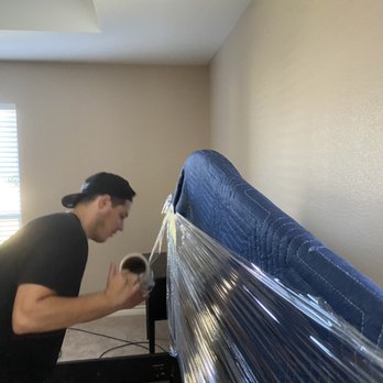 Ajax Moving Labor - Alek wrapping a headboard to prep for transport. - Movers Near Me