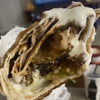 Shawerma Bite - Chicken shawarma with garlic sauce - A chicken shawarma wrap with garlic sauce is shown, with visible layers of meat, vegetables, and sauce, in a casual indoor setting. - Mediterranean Near Me - Columbus, Ohio