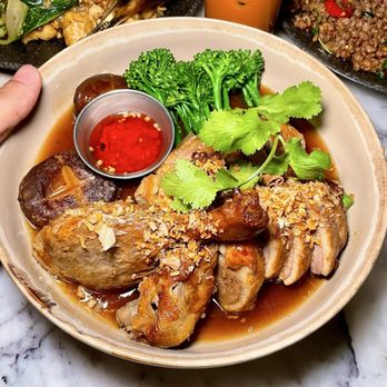 Sukh - PED TOON - A dish featuring sliced chicken with broccoli, garnished with cilantro and crushed nuts, served with chili sauce and a side of vegetables and drinks. - Thai Near Me - Brooklyn, New York