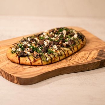 The Artisan - a piece of pizza on a cutting board - Bars Near Me - Dallas, Texas The Artisan - a piece of pizza on a cutting board - Bars Near Me - Dallas, Texas
