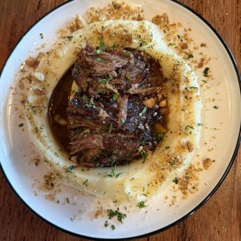 Fulano - Vacio (slow cooked beef in a Malbec reduction nestled in a ring of mashed potatoes) - A dish featuring tender beef in a Malbec wine sauce, surrounded by a ring of mashed potatoes and garnished with herbs and crumbs. - Argentine Near Me - Key Biscayne, Florida