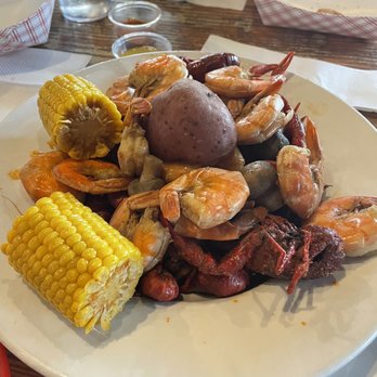 Buffalo Run - Crawfish with shrimp and fixings - A seafood boil plate with crawfish, shrimp, corn on the cob, and a potato, served on a white dish at a restaurant. - Sports Bars Near Me - Spring, Texas