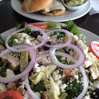 The Grotto - Greek salad with chicken (foreground), spicy chicken sandwich with side Caesar in background. - American Near Me - Springfield, Missouri The Grotto - Greek salad with chicken (foreground), spicy chicken sandwich with side Caesar in background. - American Near Me - Springfield, Missouri