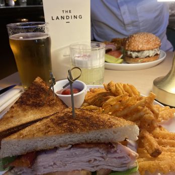 The Landing - Turkey Club (front) w/ the Von Trapp Pilsner & 8oz Sirloin Burger (back) w/ "The OG". - Cocktail Bars Near Me - New York, New York The Landing - Turkey Club (front) w/ the Von Trapp Pilsner & 8oz Sirloin Burger (back) w/ "The OG". - Cocktail Bars Near Me - New York, New York