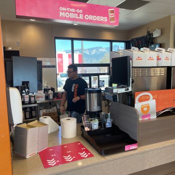Dunkin' -  a man standing behind a counter in a donut shop - Donuts Near Me - Bernalillo, New Mexico