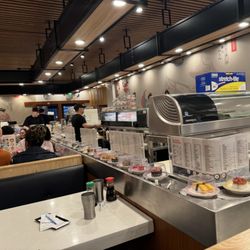 Izumi Kaiten Sushi - Extra plates are seen in the background staked up on top of that fridge.   There were only 2 other groups.  Why leave more raw fish out!