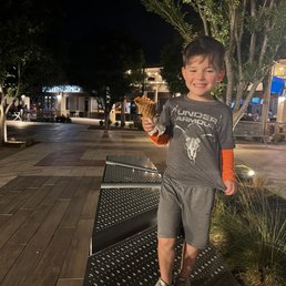 A cute kid with a delicious scoop of chocolate ice cream in a homemade waffle cone!