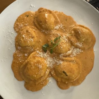 From Scratch - Lobster Raviolli - Lobster ravioli served with a rich, orange-colored sauce, topped with grated cheese and a small herb garnish, on a white plate. - Pizza Near Me - Boston, Massachusetts