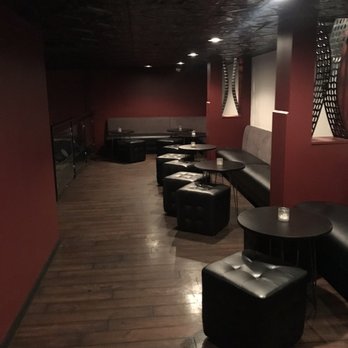 Howard & Fine - a long room with black leather seating and red walls - Speakeasies Near Me - Omaha, Nebraska
