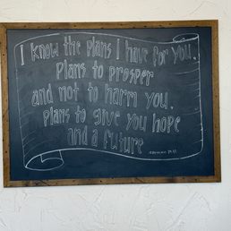 Beautiful scripture displayed - A chalkboard displays a quote from Jeremiah 29:11 written in white chalk, framed with wood, mounted on a textured white wall.