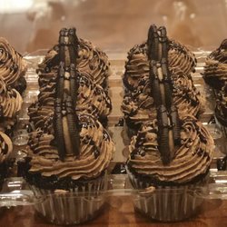 All Baked Out - Chocolate lovers dream cupcakes, chocolate with chocolate buttercream drizzled with chocolate syrup topped with a chocolate Oreo cookie