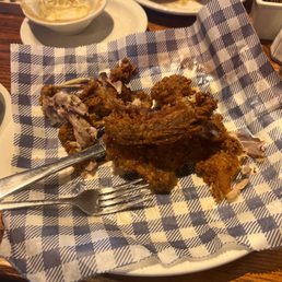 Southern Fried Chicken Family Meal - Fried chicken pieces are served on a checkered paper-lined plate, with some bones visible, in a restaurant setting.